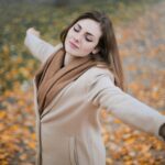 A young woman enjoying freedom in an autumn park, symbolizing breaking free from routine and embracing a new journey