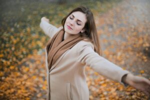 A young woman enjoying freedom in an autumn park, symbolizing breaking free from routine and embracing a new journey